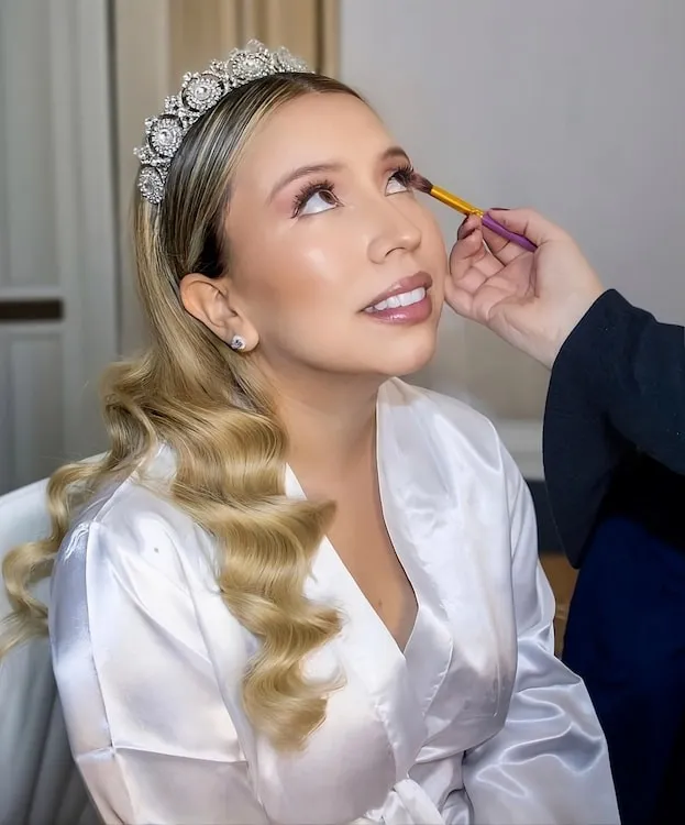 Novia con tiara recibiendo maquillaje profesional