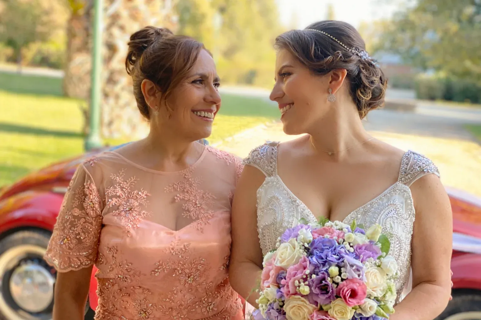 Novia y su madre sonriendo con maquillaje y peinado profesional el día del matrimonio