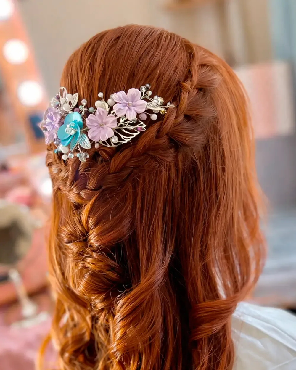 Tocado tipo peineta con flores pastel, perlas decorativas y hojas metálicas en composición floral elegante